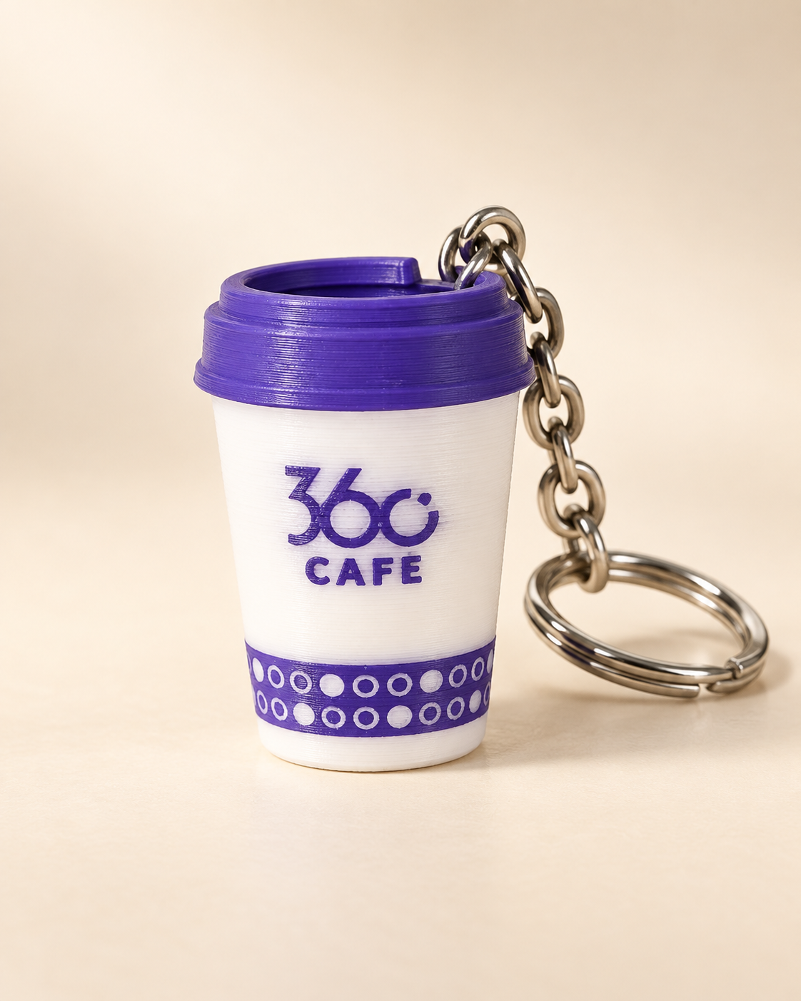 ميدالية 360 Café البيضاء بغطاء وشعار بنفسجي وشريط سفلي منقوش، مع سلسلة وحلقة معدنية
